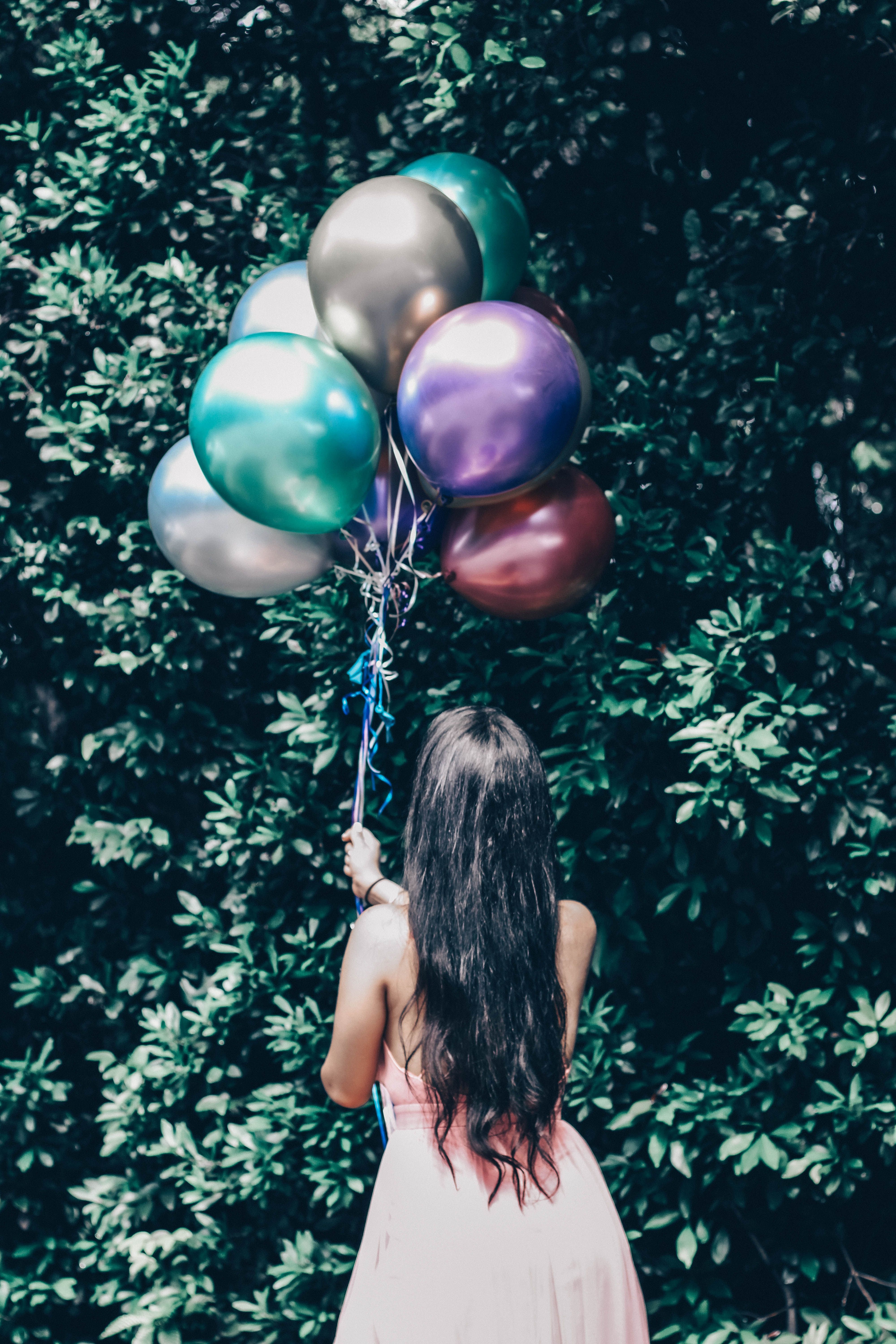 Frida Lopez de espaldas sosteniendo globos frente a la vegetación